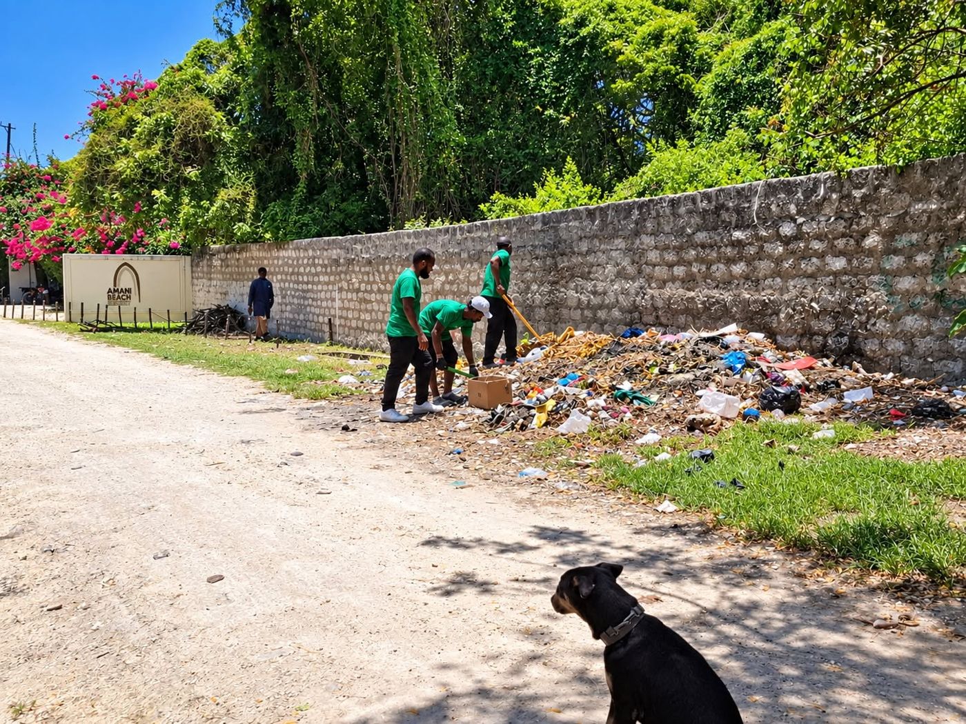 Litter piled along a wall on a road in Watamu, with the KEWASTE crew starting to clear it